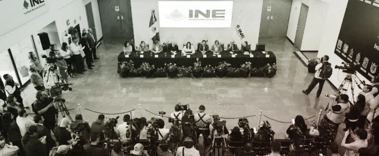 Sala del Consejo General del INE con una mesa en forma de herradura y una silla vacía en la cabecera