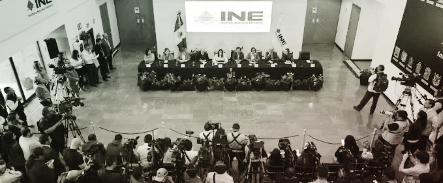 Sala del Consejo General del INE con una mesa en forma de herradura y una silla vacía en la cabecera