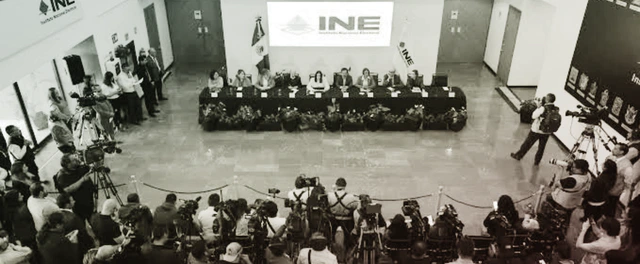 Sala del Consejo General del INE con una mesa en forma de herradura y una silla vacía en la cabecera